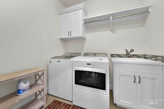 laundry room with cabinet space, separate washer and dryer, a sink, and wood finished floors