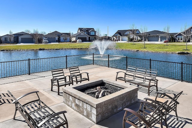 view of patio with an outdoor fire pit, a water view, and a residential view