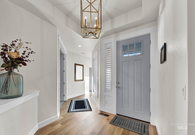 foyer with recessed lighting, visible vents, baseboards, light wood finished floors, and a raised ceiling