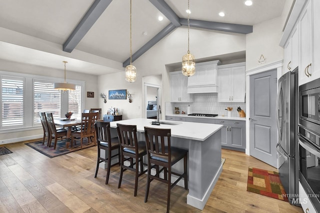 kitchen featuring light countertops, appliances with stainless steel finishes, a sink, and light wood-style floors