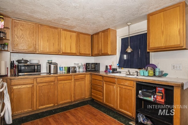 kitchen with sink, hanging light fixtures, dark hardwood / wood-style floors, and a textured ceiling