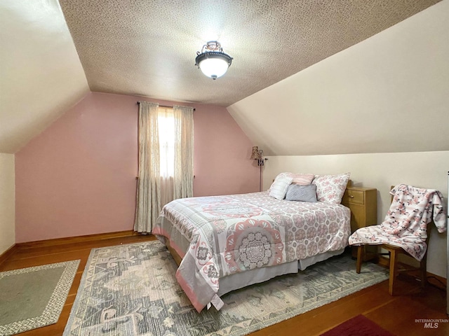 bedroom featuring baseboards, wood finished floors, and lofted ceiling