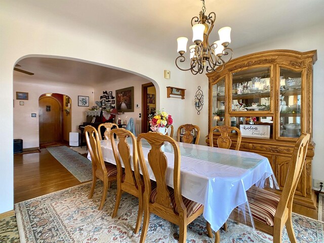 dining space with arched walkways, wood finished floors, and a chandelier
