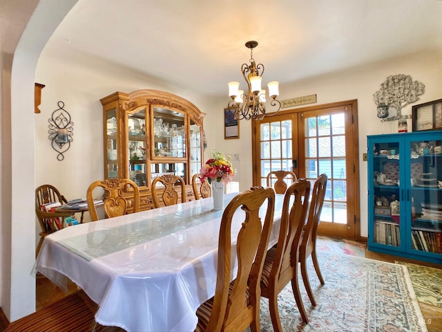 dining space featuring french doors, arched walkways, and a notable chandelier
