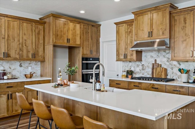 17639 N El Dorado Ave, Nampa, ID 83687 - kitchen with ventilation hood, stainless steel appliances, brown cabinets, backsplash, and recessed lighting