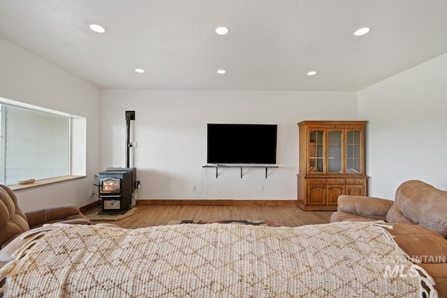 bedroom featuring a wood stove and light hardwood / wood-style floors