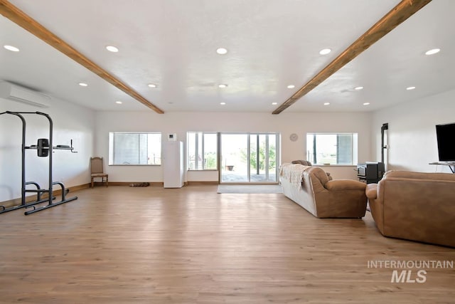 living room with hardwood / wood-style floors, beamed ceiling, and an AC wall unit