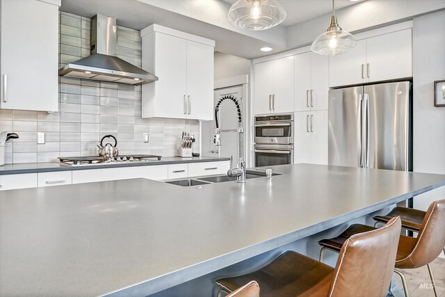 6420 W Glencrest Ln, Boise, ID 83714 - kitchen featuring stainless steel appliances, a breakfast bar, a sink, wall chimney exhaust hood, and decorative backsplash