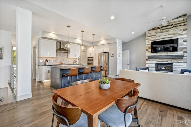 6420 W Glencrest Ln, Boise, ID 83714 - dining area with vaulted ceiling, wood finished floors, ceiling fan, a tiled fireplace, and recessed lighting