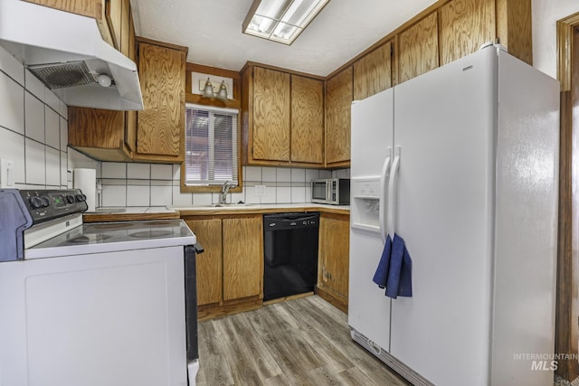 561 3rd Ave N, Twin Falls, ID 83301 - kitchen featuring white appliances, under cabinet range hood, brown cabinets, light wood-style floors, and decorative backsplash