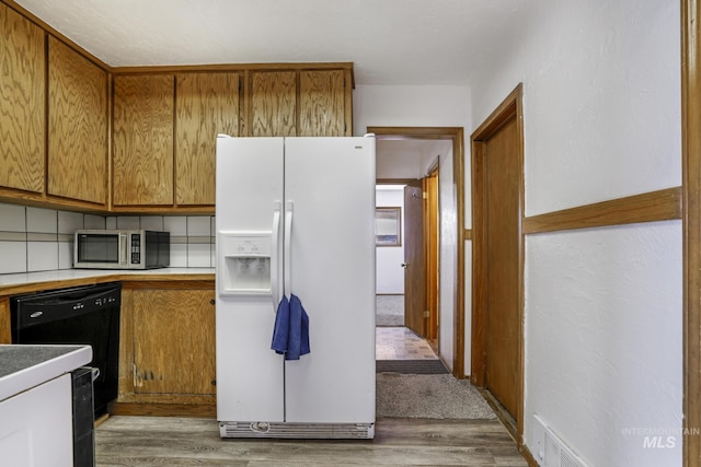 561 3rd Ave N, Twin Falls, ID 83301 - kitchen with white fridge with ice dispenser, stainless steel microwave, light wood-style floors, and brown cabinetry