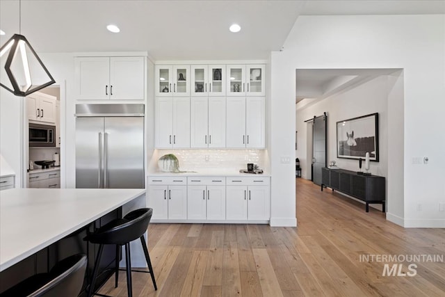 1093 N Morehouse Ave, Eagle, ID 83616 - kitchen featuring built in appliances, white cabinetry, tasteful backsplash, and light countertops