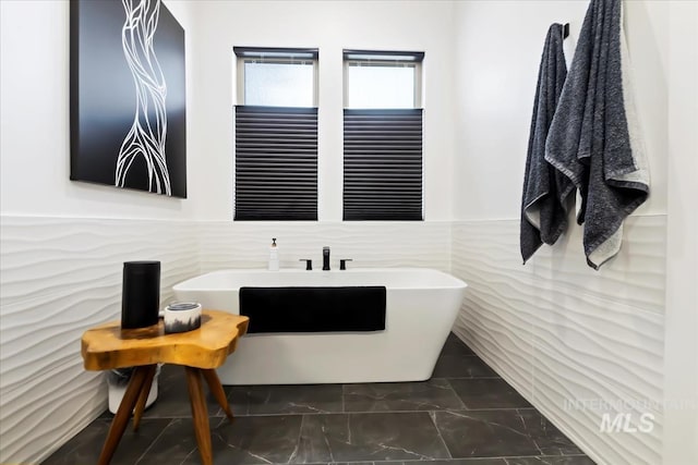 1093 N Morehouse Ave, Eagle, ID 83616 - bathroom featuring marble finish floor, a freestanding tub, a wainscoted wall, and tile walls