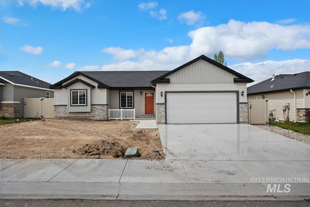 ranch-style home with covered porch, stone siding, a gate, an attached garage, and driveway