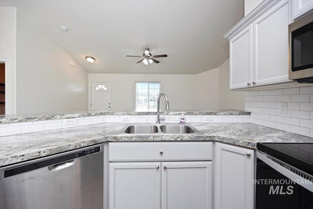 kitchen featuring a ceiling fan, appliances with stainless steel finishes, tasteful backsplash, a sink, and white cabinets