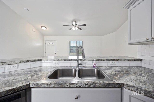 kitchen with backsplash, ceiling fan, stone countertops, and a sink