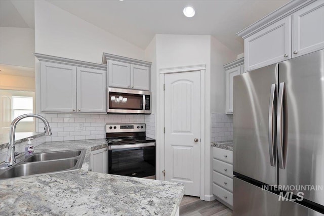 kitchen featuring wood finished floors, recessed lighting, tasteful backsplash, a sink, and stainless steel appliances