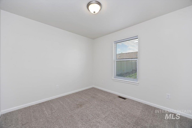 spare room featuring carpet flooring, baseboards, and visible vents