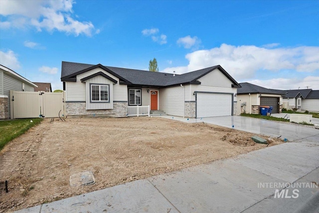 single story home with driveway, a gate, fence, an attached garage, and stone siding