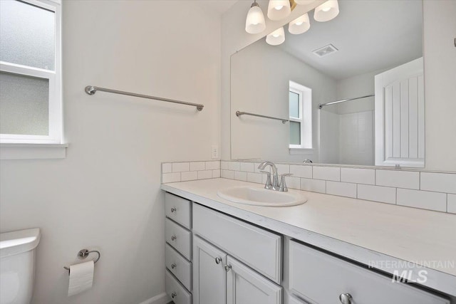 full bath with toilet, visible vents, tasteful backsplash, and vanity