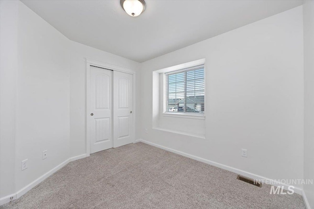 unfurnished bedroom with carpet floors, baseboards, visible vents, and a closet