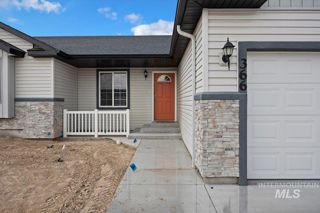 doorway to property featuring a garage, a porch, roof with shingles, and stone siding