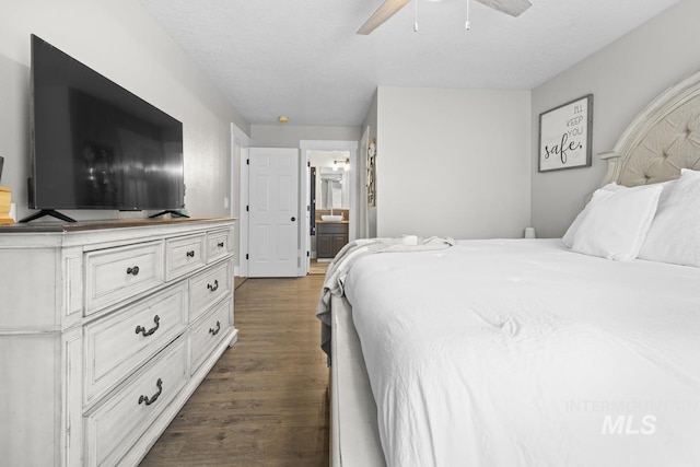 bedroom with a textured ceiling, ensuite bathroom, ceiling fan, and dark wood-type flooring