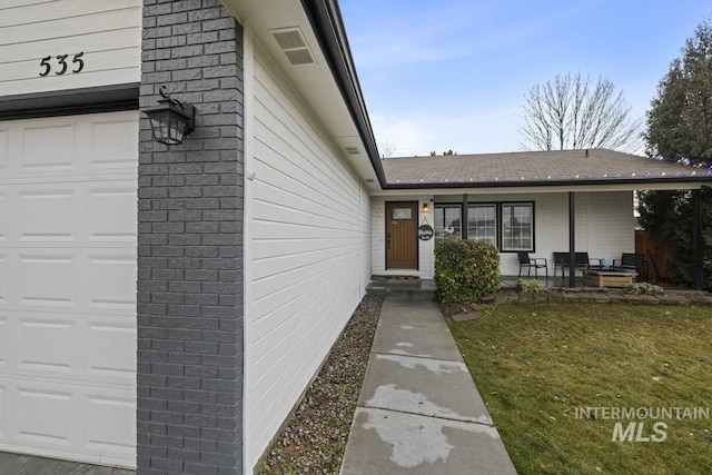 view of exterior entry featuring a lawn and a garage