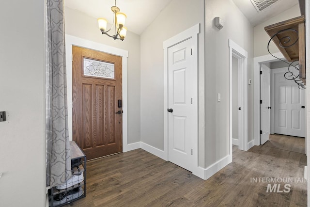 foyer entrance featuring a chandelier, dark hardwood / wood-style floors, and vaulted ceiling