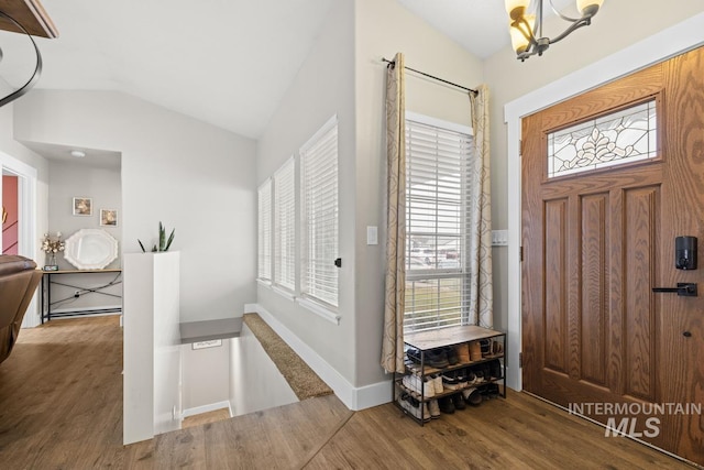 entryway with a chandelier, wood-type flooring, and lofted ceiling