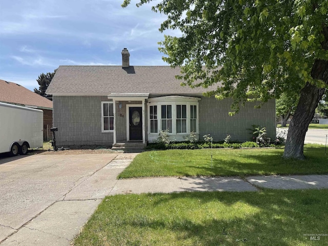104 E B St, Shoshone, ID 83352 - view of front of house with a front yard, a chimney, and roof with shingles
