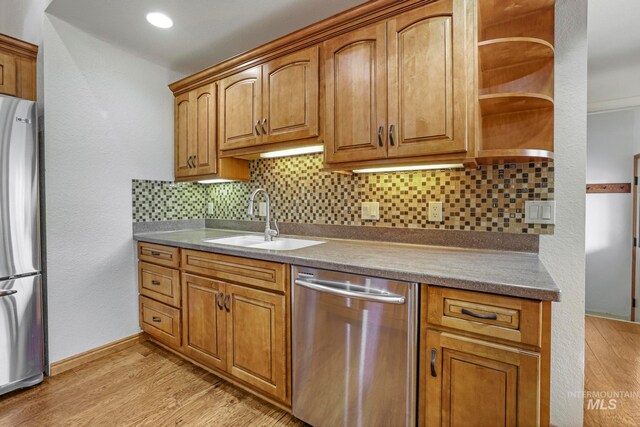 kitchen featuring sink, decorative backsplash, light hardwood / wood-style flooring, and appliances with stainless steel finishes