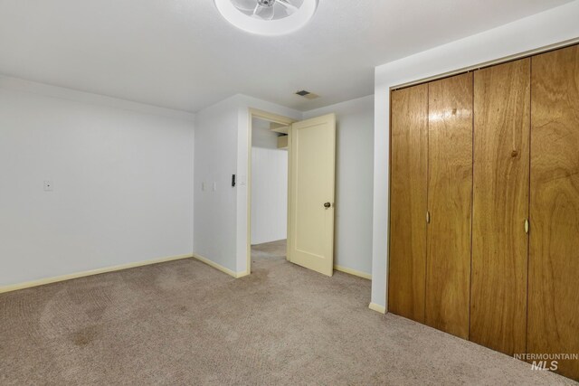 unfurnished bedroom featuring light colored carpet and a closet