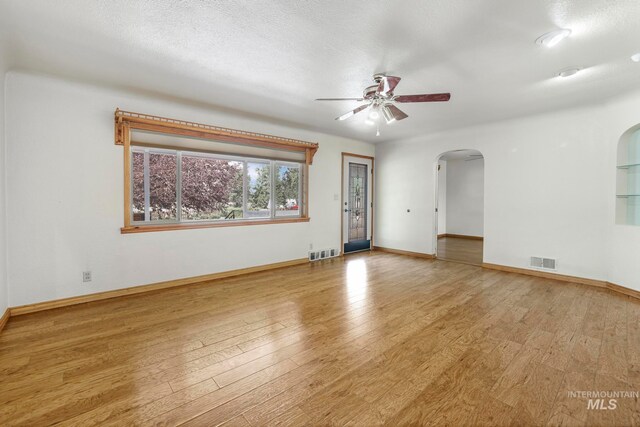 unfurnished room with ceiling fan, a textured ceiling, and light wood-type flooring