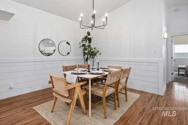 dining area with a chandelier, vaulted ceiling, and wood-type flooring