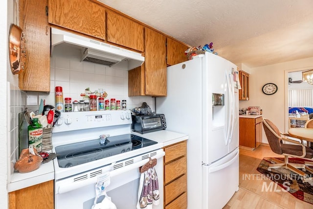 392 S Sun Burst Way, Boise, ID 83709 - kitchen with white appliances, under cabinet range hood, light countertops, brown cabinets, and backsplash