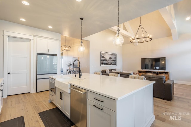 kitchen with white cabinetry, hanging light fixtures, white refrigerator, stainless steel dishwasher, and a kitchen island with sink