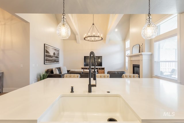 kitchen with pendant lighting, sink, a kitchen island with sink, and a fireplace