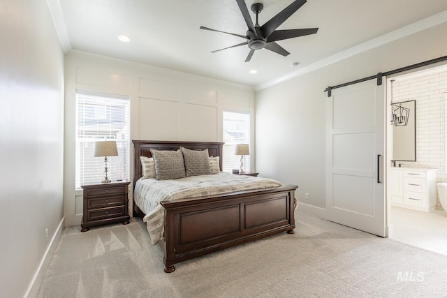 carpeted bedroom with crown molding, ceiling fan, ensuite bathroom, and a barn door