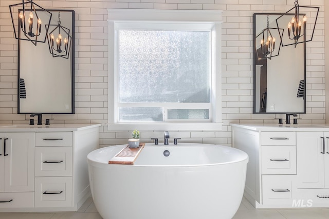 bathroom with vanity, a notable chandelier, tile walls, and a bathing tub