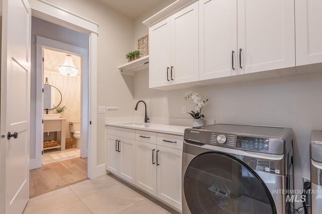 laundry room featuring sink, cabinets, independent washer and dryer, and light tile patterned flooring