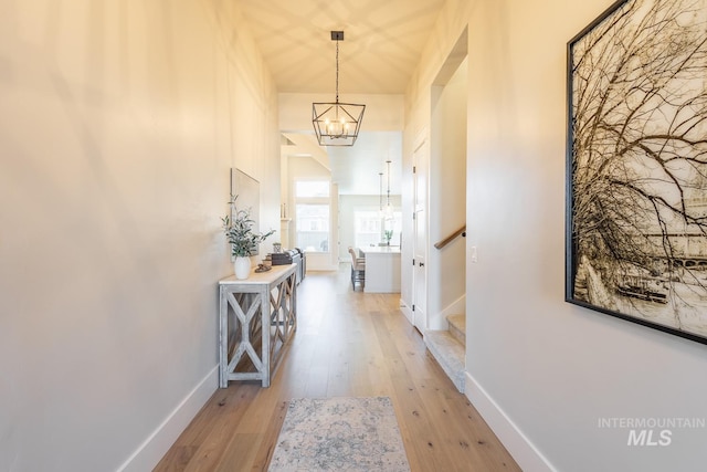 corridor with light hardwood / wood-style flooring and a chandelier