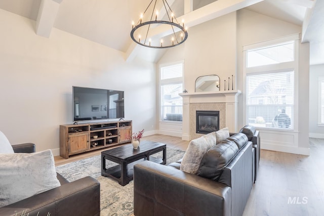 living room featuring beamed ceiling, a tiled fireplace, high vaulted ceiling, and light hardwood / wood-style flooring