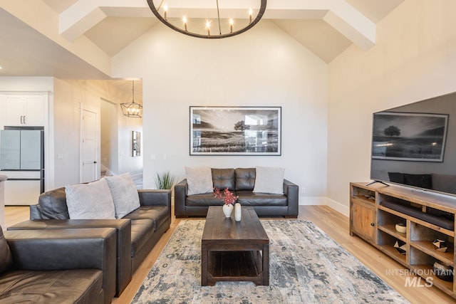 living room with high vaulted ceiling, a chandelier, and light hardwood / wood-style floors