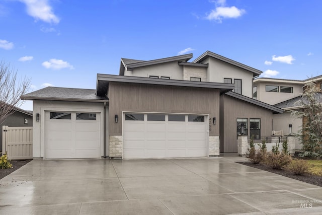 view of front of house featuring a garage, driveway, stone siding, and fence