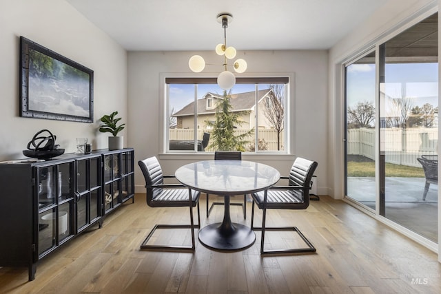 dining area featuring baseboards, light wood finished floors, and a healthy amount of sunlight