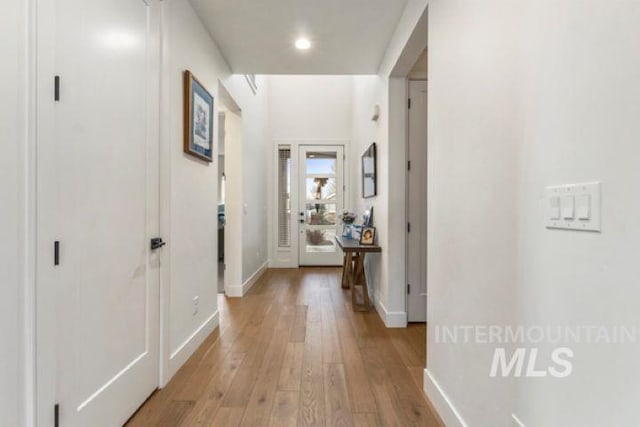 corridor featuring light wood finished floors and baseboards