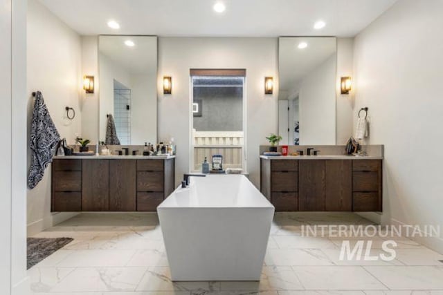 full bathroom with a soaking tub, marble finish floor, two vanities, and recessed lighting