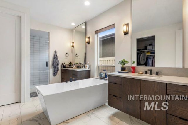 full bathroom with marble finish floor, recessed lighting, a soaking tub, and vanity