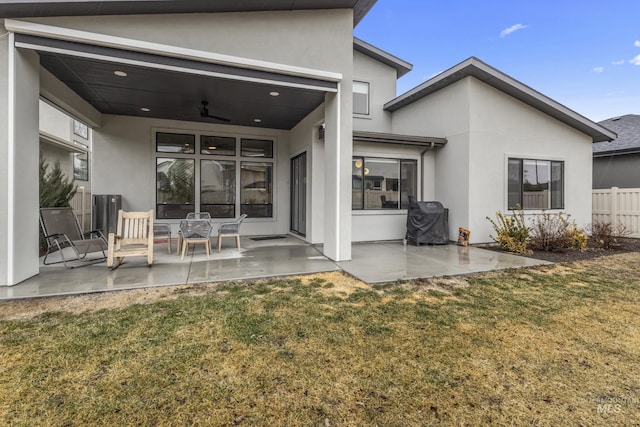 rear view of property featuring a patio area, ceiling fan, a yard, and stucco siding